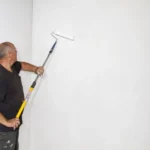 Schilder- en Gyprocwerken 1 Schilder verft de muur in een witte kleur